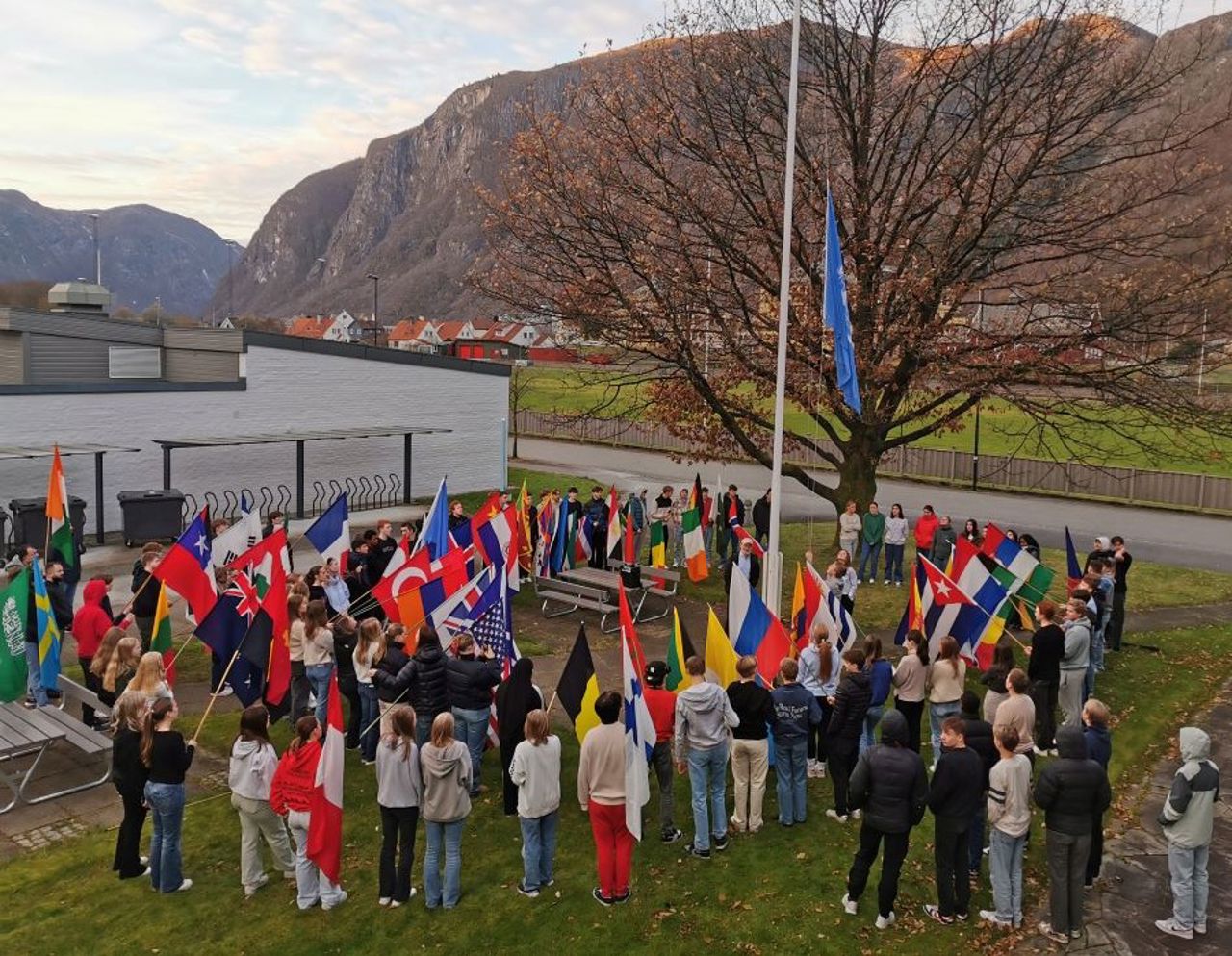 Elevar heiser FN flagget og står rundt flaggstanga med flagg frå heile verda