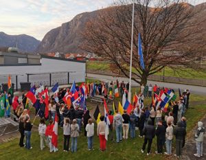 Elevar heiser FN flagget og står rundt flaggstanga med flagg frå heile verda