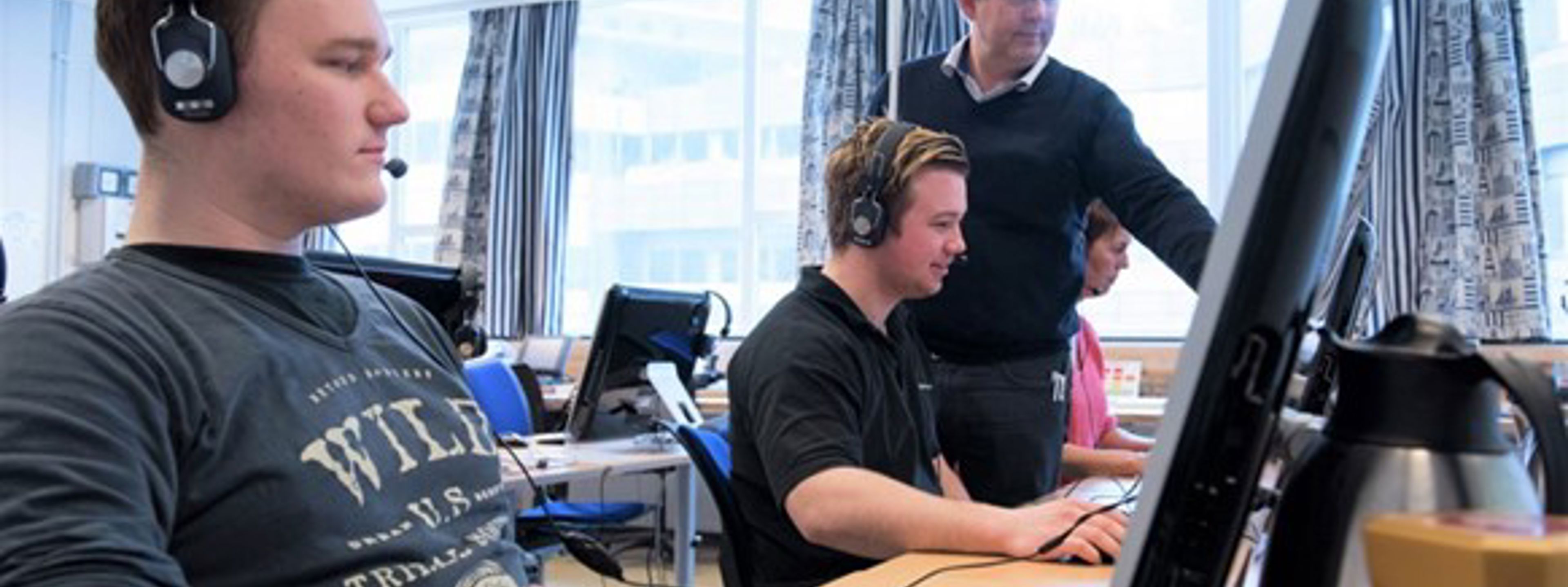 To elevar sit framfor PC'en med ein lærar ved siden av