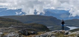 Ein elev står på ein fjelltopp og ser utover