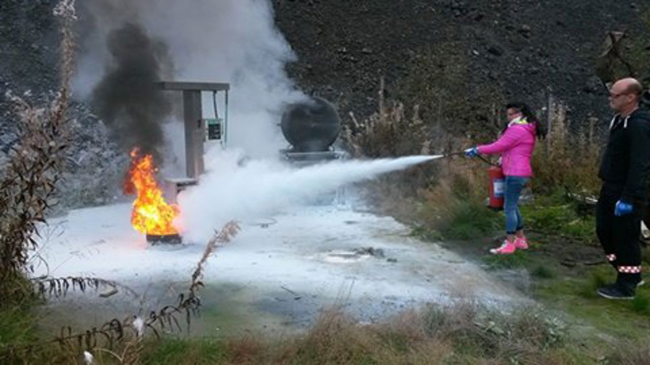 Ein person slukkar brann med brannslukningsapparat i lag med ein instruktør.