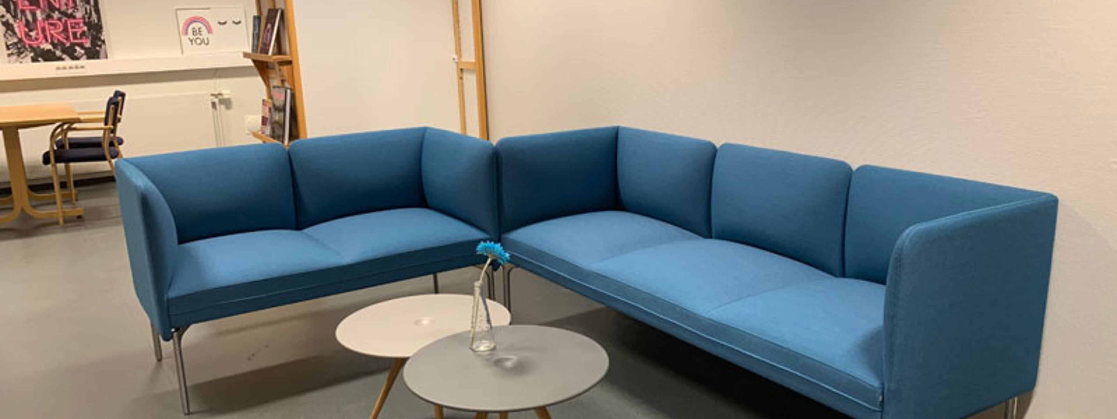 Blå vinkelsofa inne på eit bibliotek