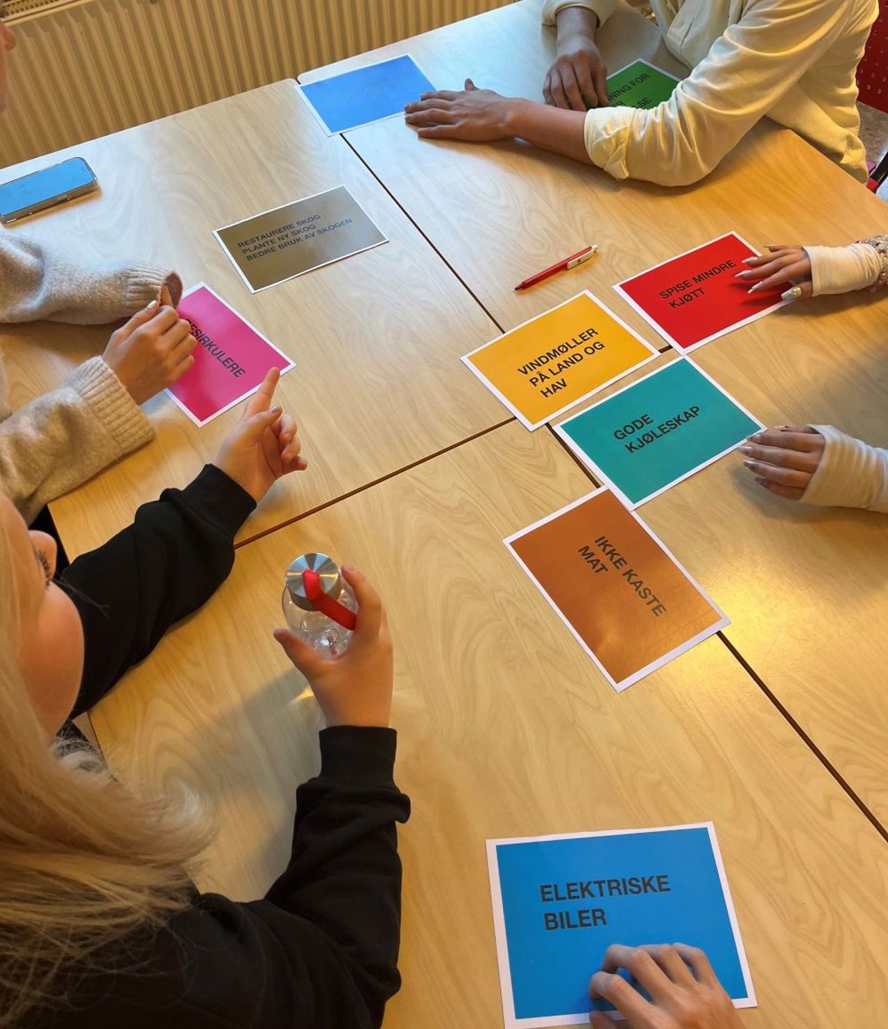 Elevar sit rundt eit bord med farga lappar som handlar om bærekraft