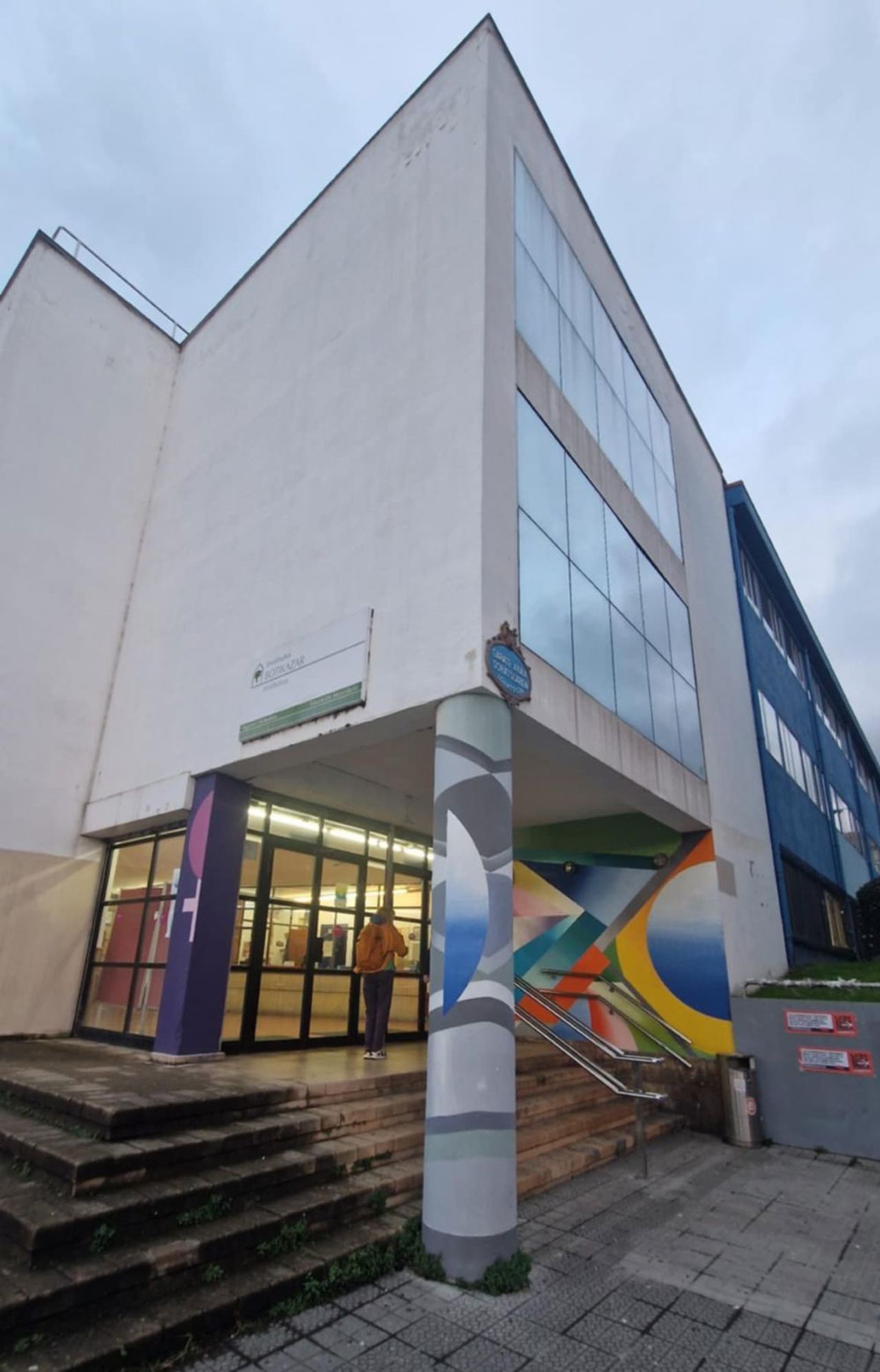 Skulen dei vitja i Bilbao. Kvit bygning med kunstmotiv ved inngangen