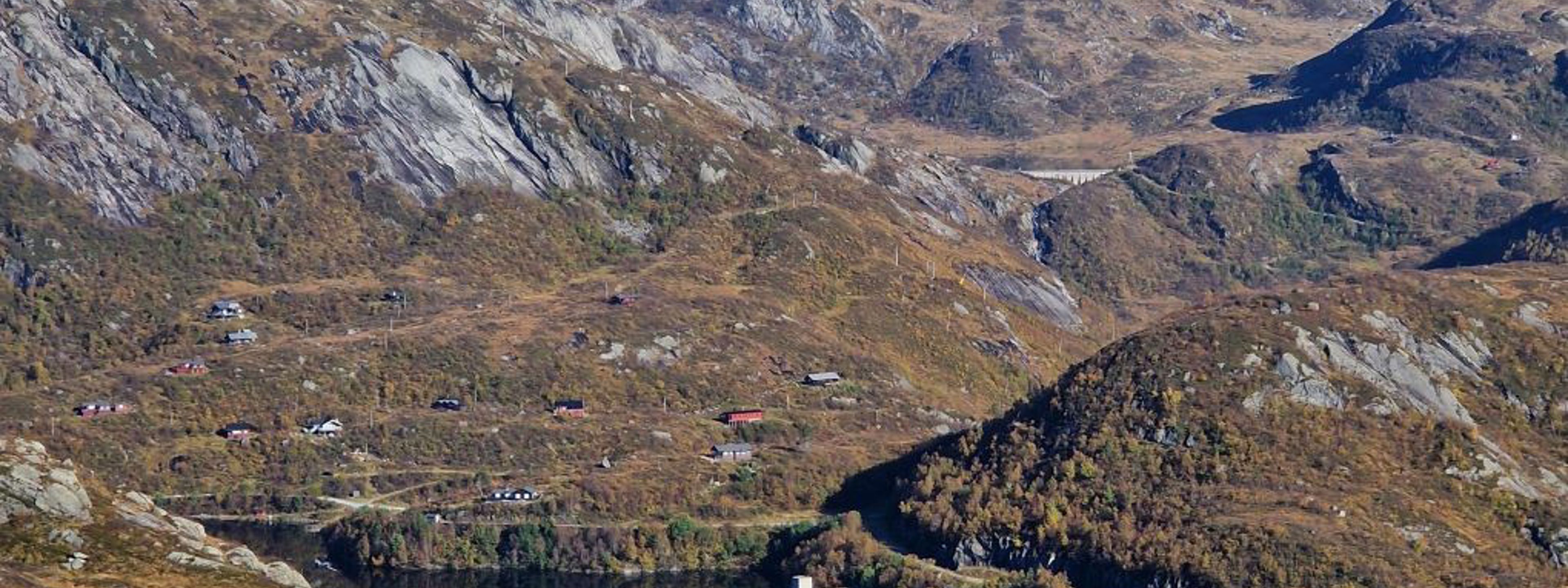 Fjellandskap med blå himmet og eit vatn og ein demning