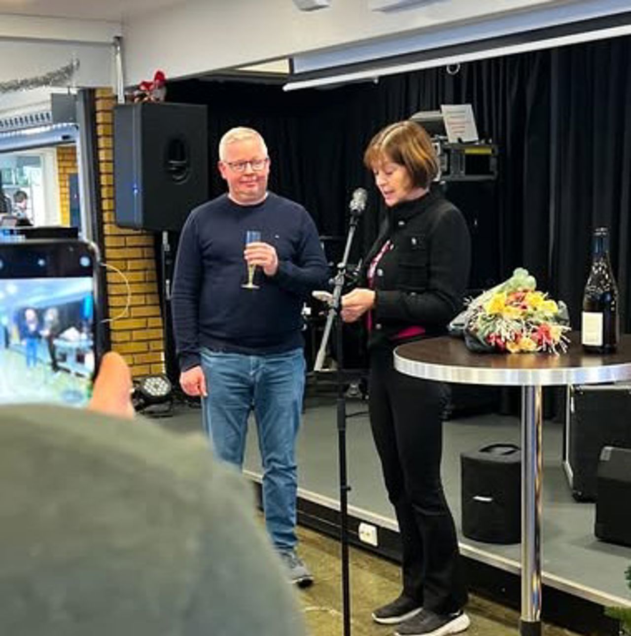 To personar på ei scene kor ein av dei mottek ein pris